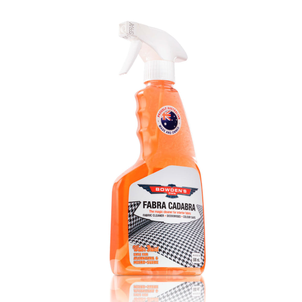 An orange spray bottle of Bowden's Own Fabra Cadabra fabric cleaning solution with black & white houndstooth fabric on the label and a white spray nozzle.
